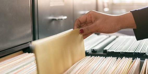 Hand zieht Akte aus einem Register